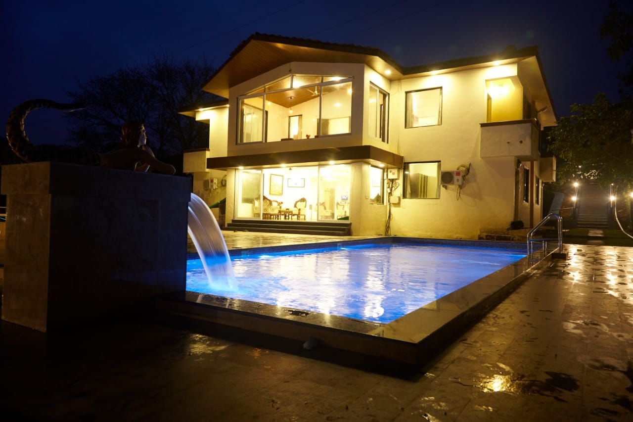 Manas Bungalow lit up at night above its pool in Igatpuri